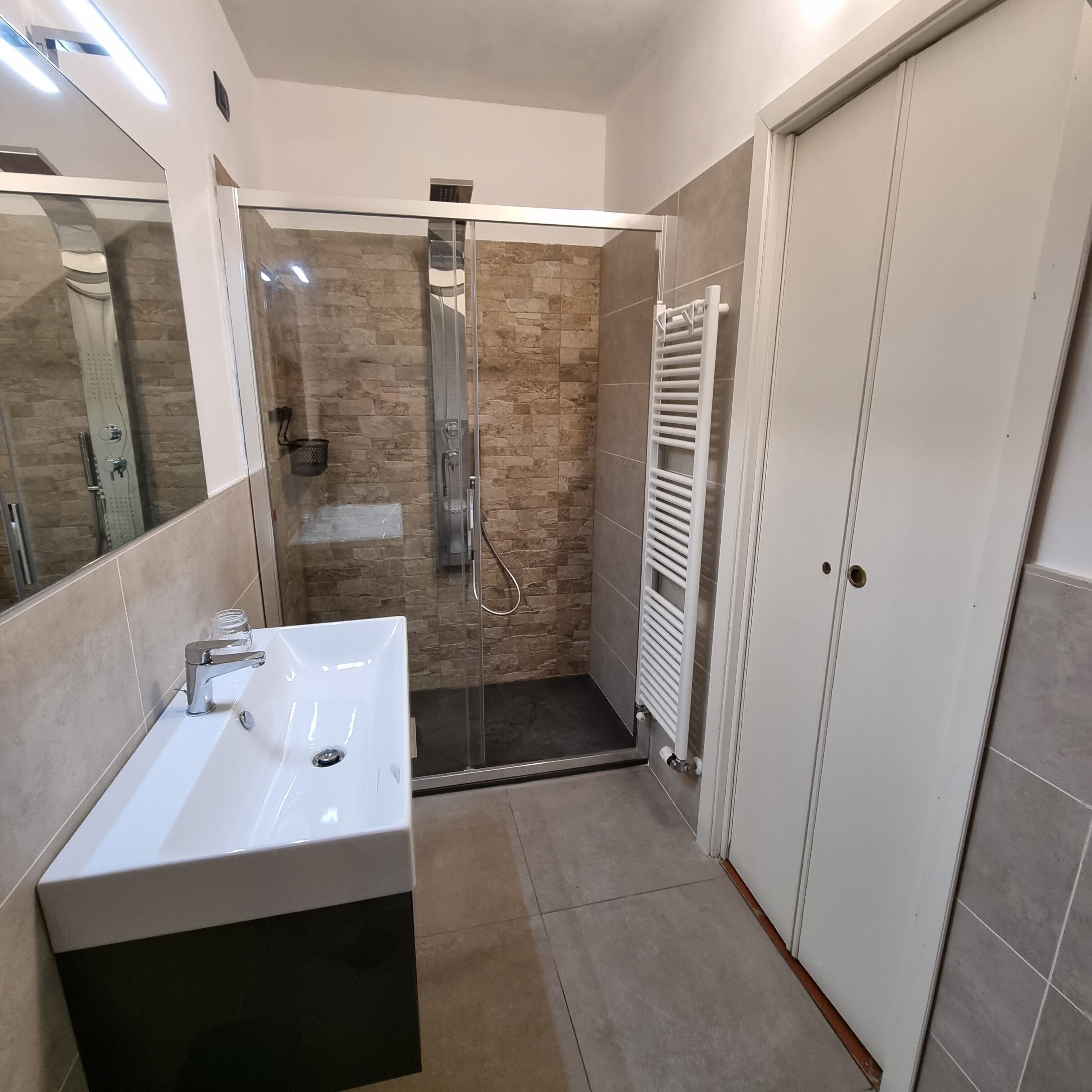 Une salle de bain moderne dotée d’un grand lavabo, d’une cabine de douche en verre et d’une douche à l’italienne.