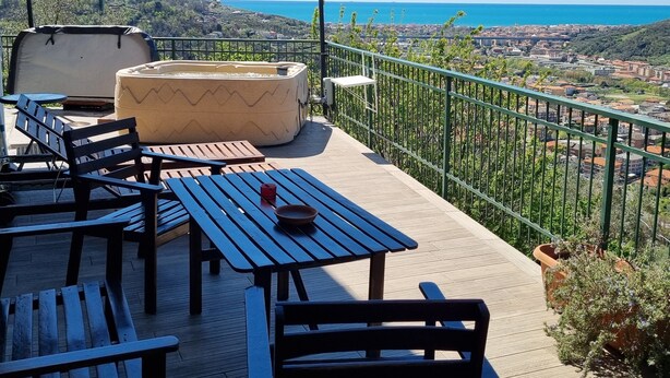 A terrace with outdoor seating, a fire pit, and a view of the sea and city. - B&B La Terrazza Sui Fieschi (Cogorno)