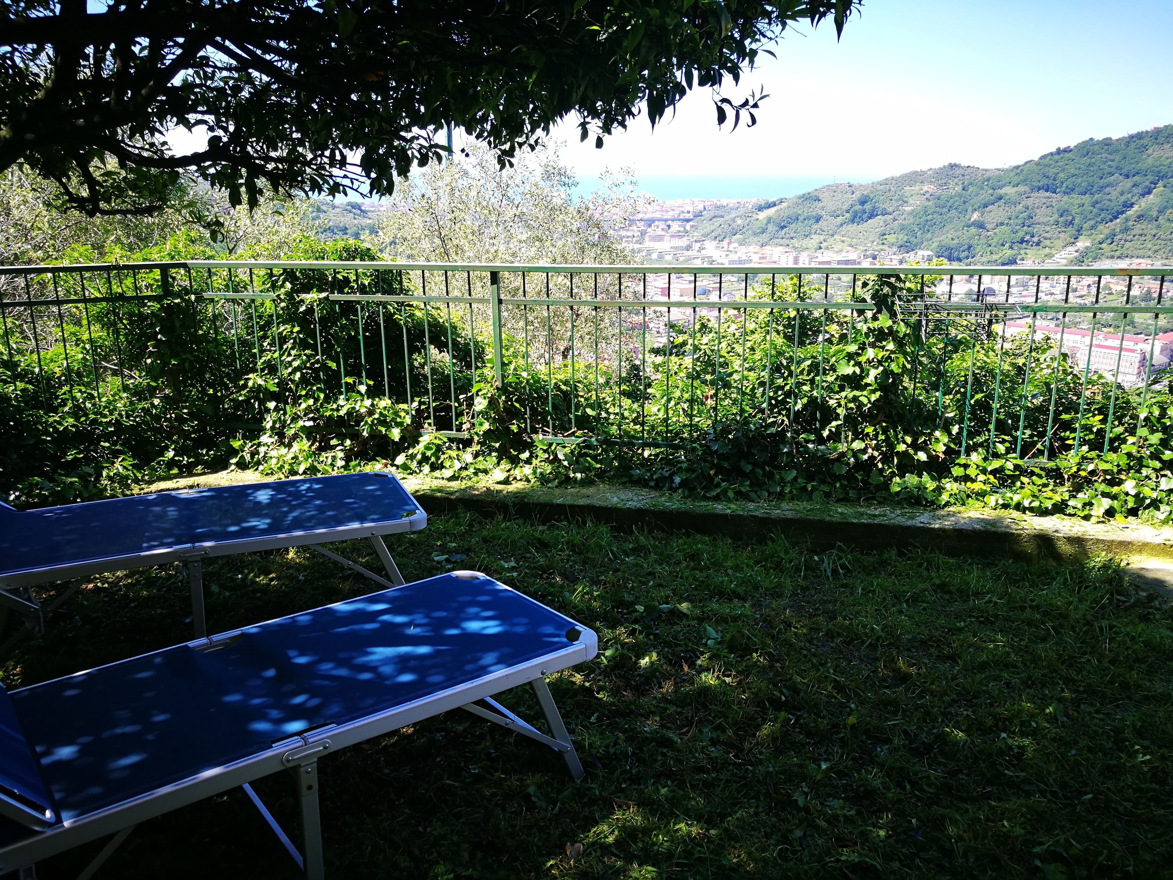 Vista desde un balcón con barandilla de metal, sobre un paisaje urbano y colinas.