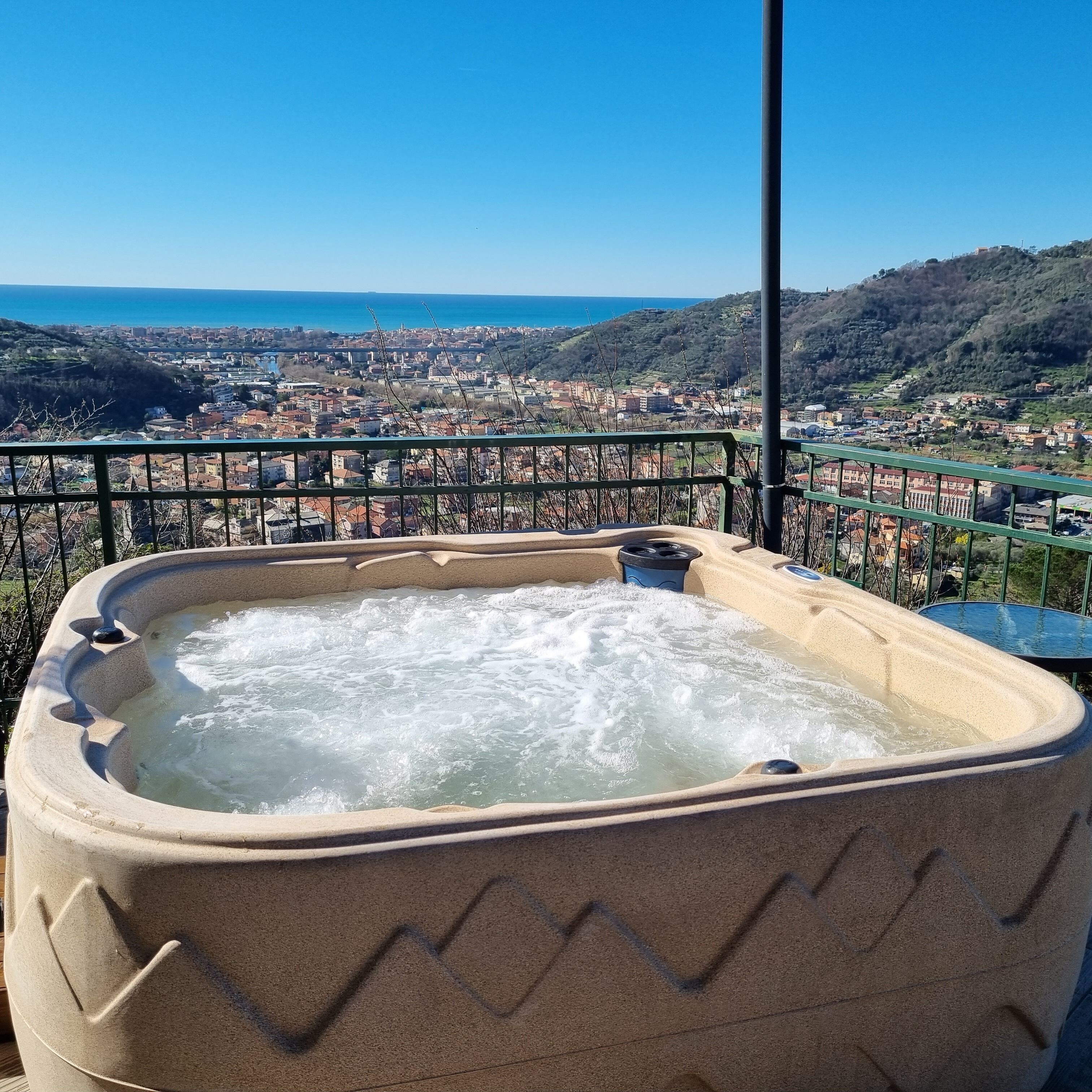 A hot tub with a view of a coastal town and hills.