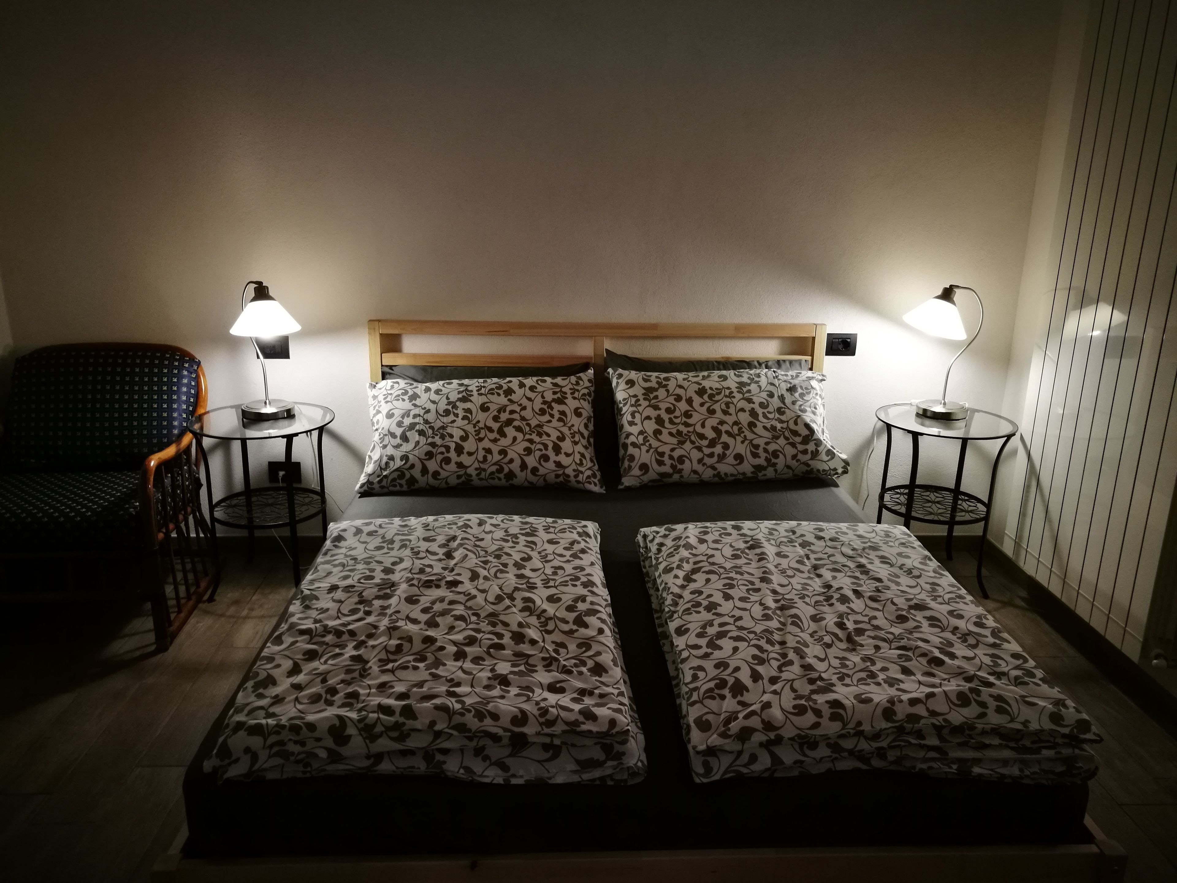 A room with a bed, two bedside tables, a chair, and two lamps.