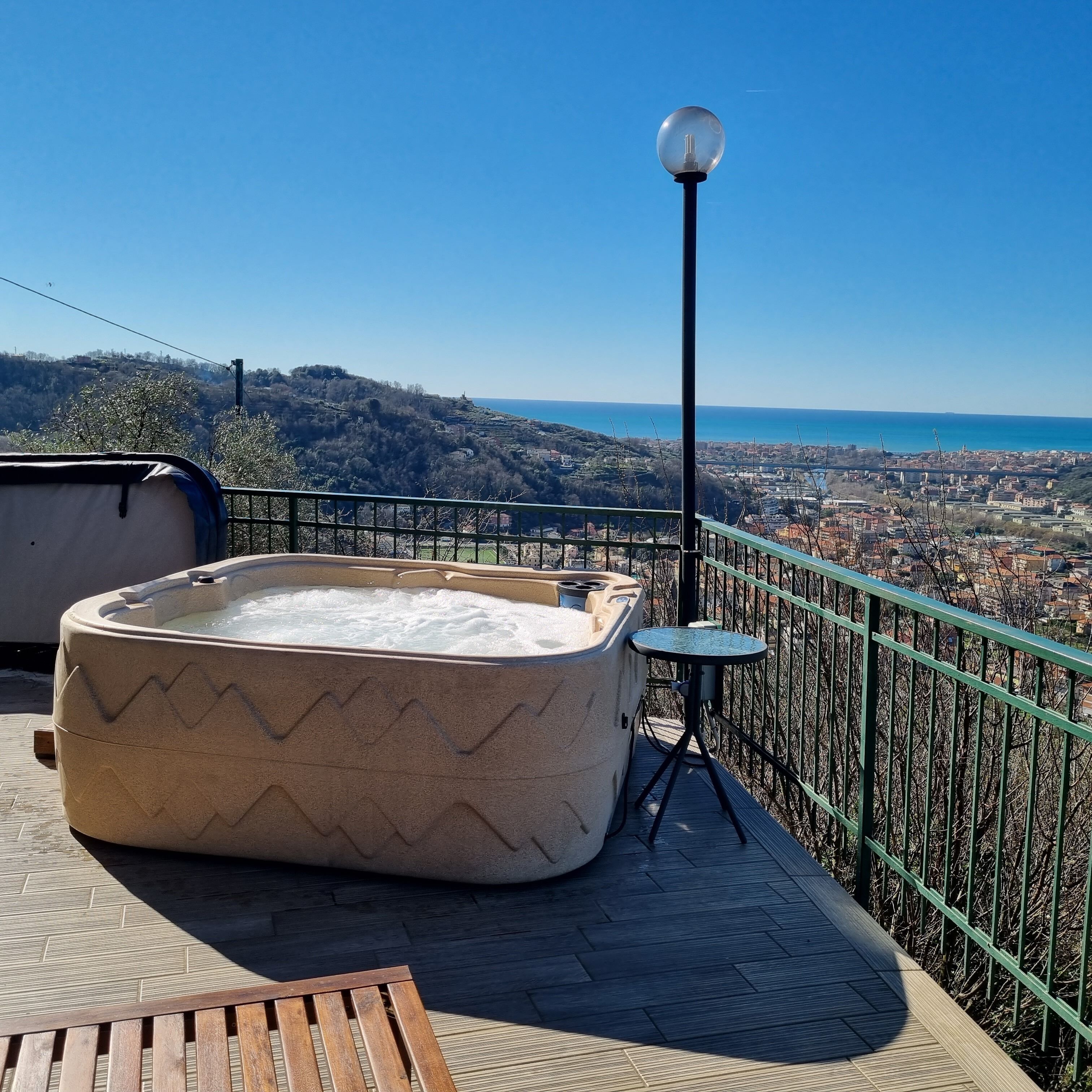 Een bubbelbad op een balkon met uitzicht op een kustplaats.