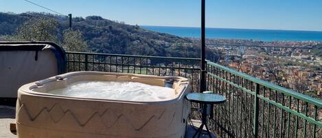 A hot tub on a balcony with a view of a coastal city.