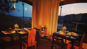 Ein Essbereich mit Tisch für zwei Personen, mit Blick auf eine Stadtlandschaft im Abenddämmerung.