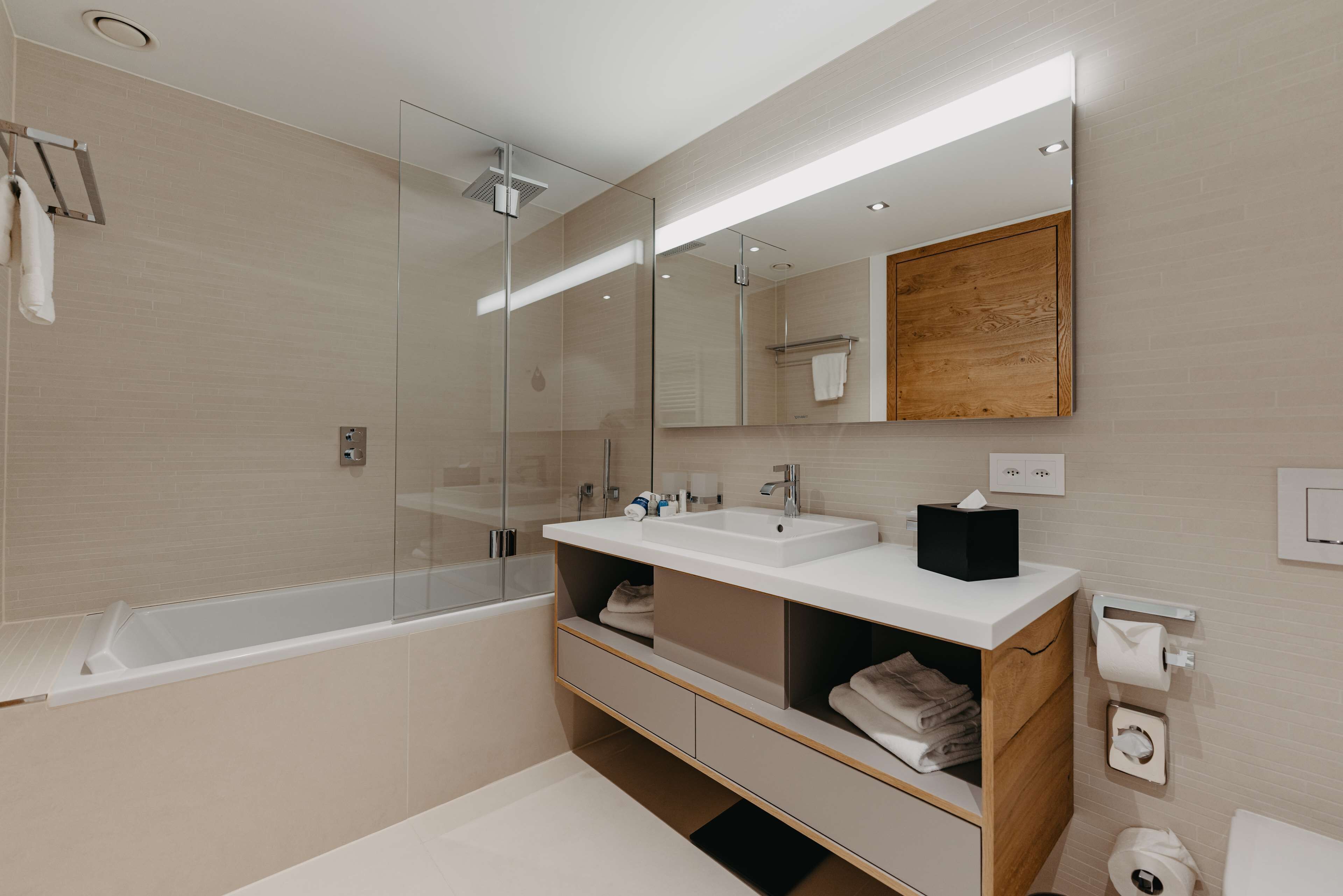 A modern bathroom with a glass-enclosed shower, a freestanding bathtub, and a vanity with storage.