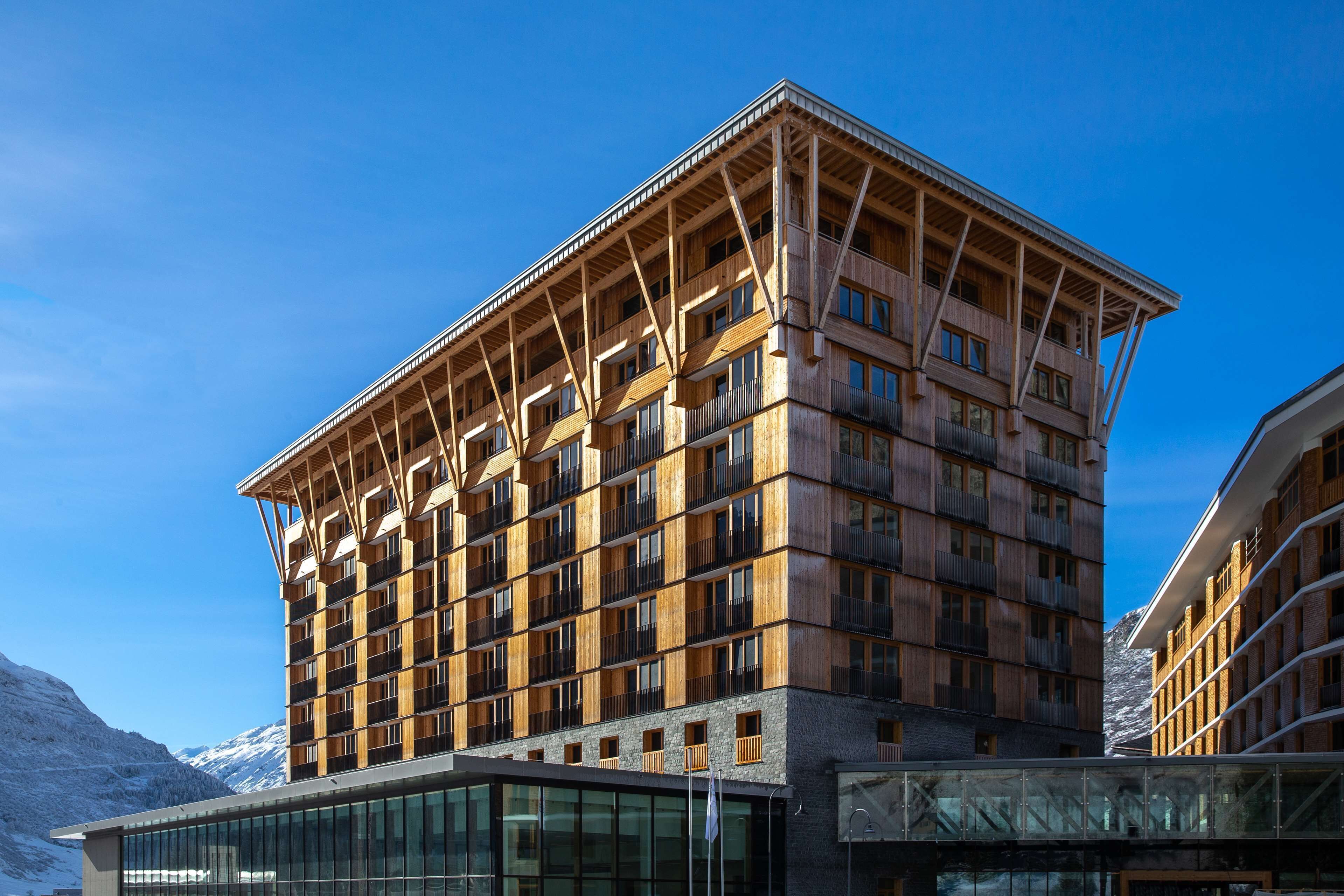 A multi-story hotel with a wooden facade, large windows, and a modern glass entrance.