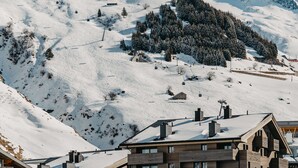 Un edificio de varios pisos con una pista de esquí al fondo.