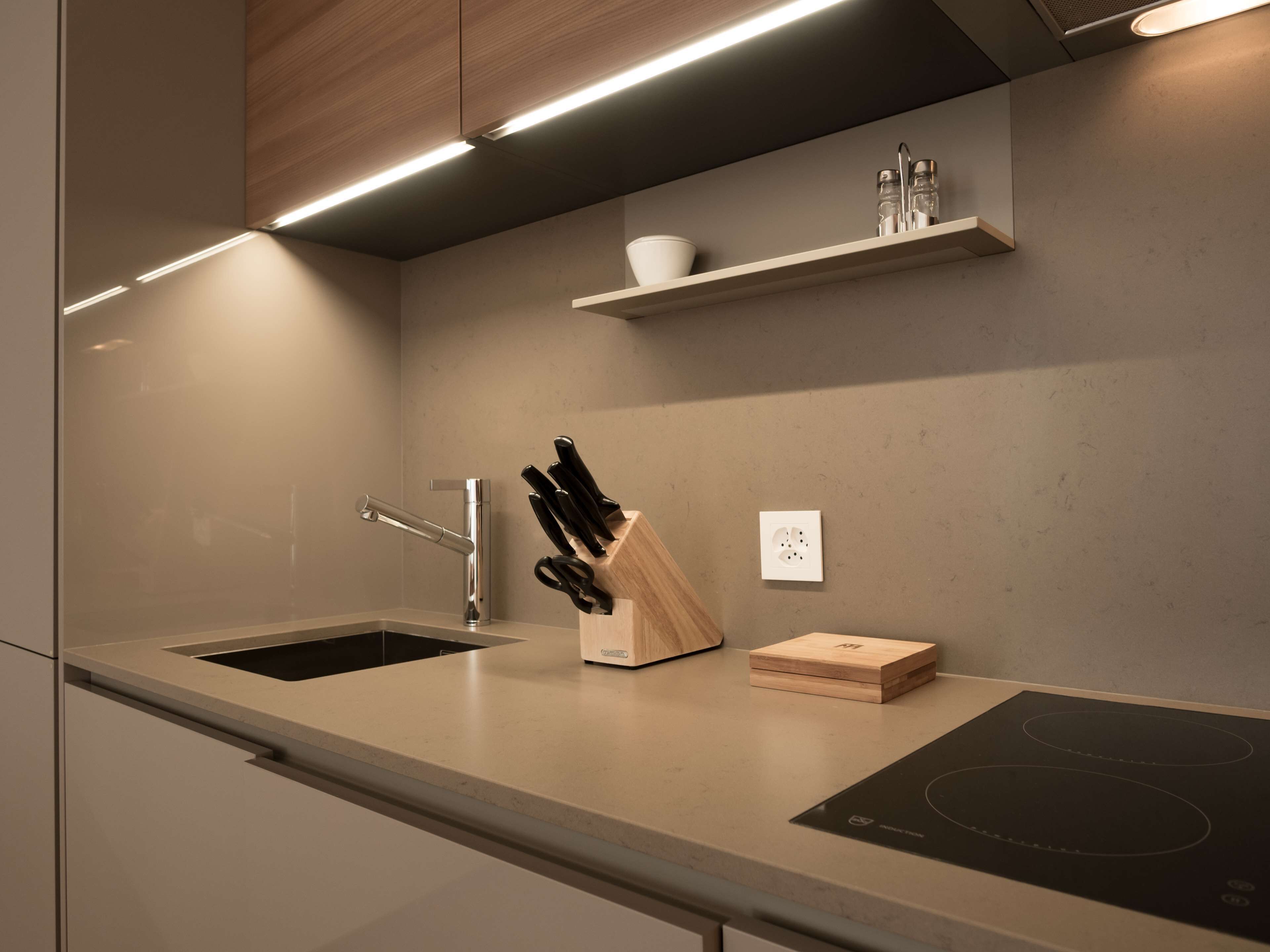 A modern kitchen with a built-in sink, a knife block, and a countertop with a built-in induction cooktop.