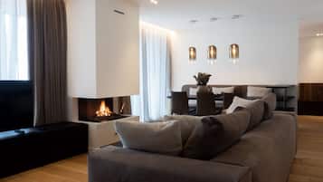 A modern living room with a fireplace, a sofa, a dining area, and pendant lights.