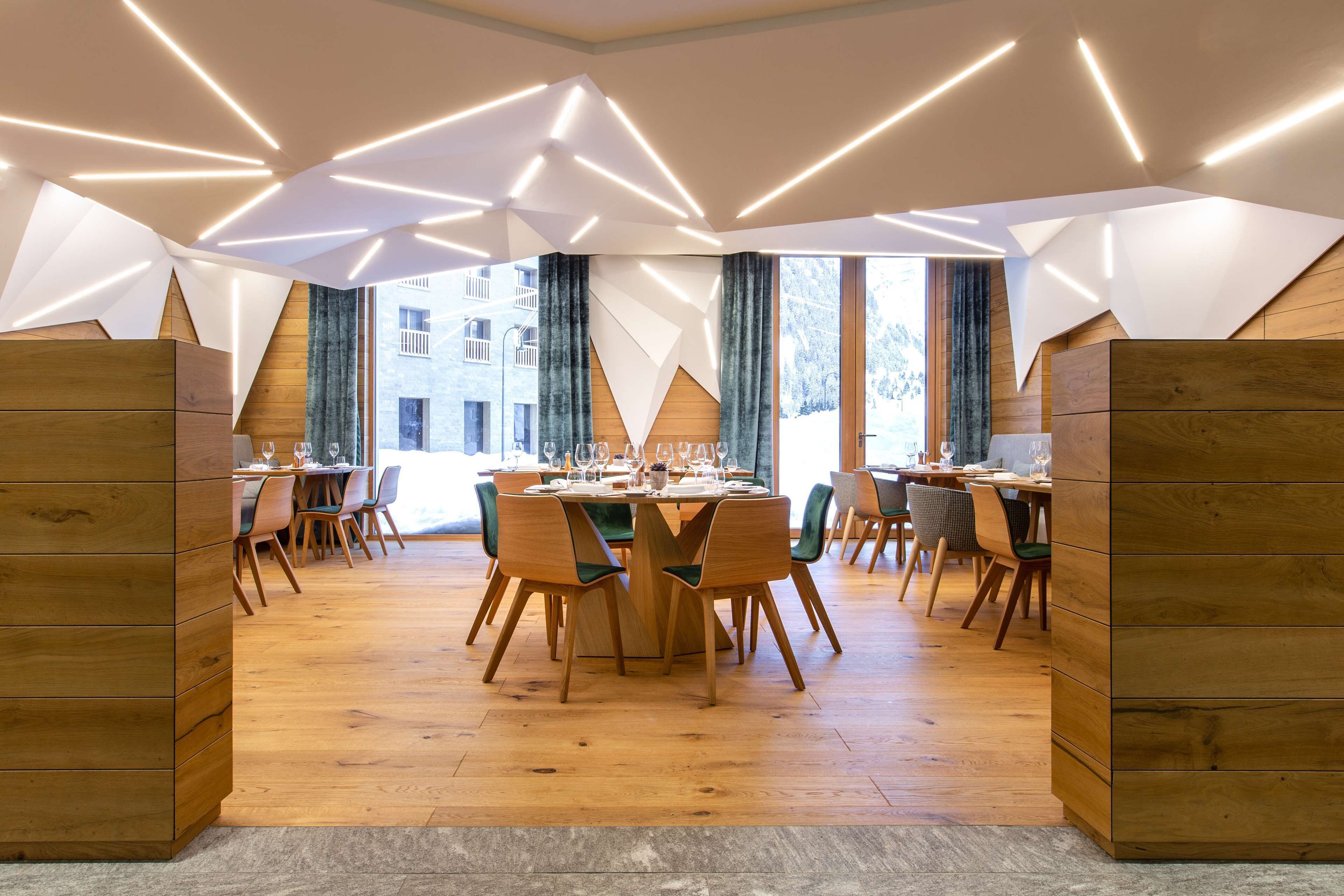 A modern dining area with wooden furniture and geometric ceiling lighting.