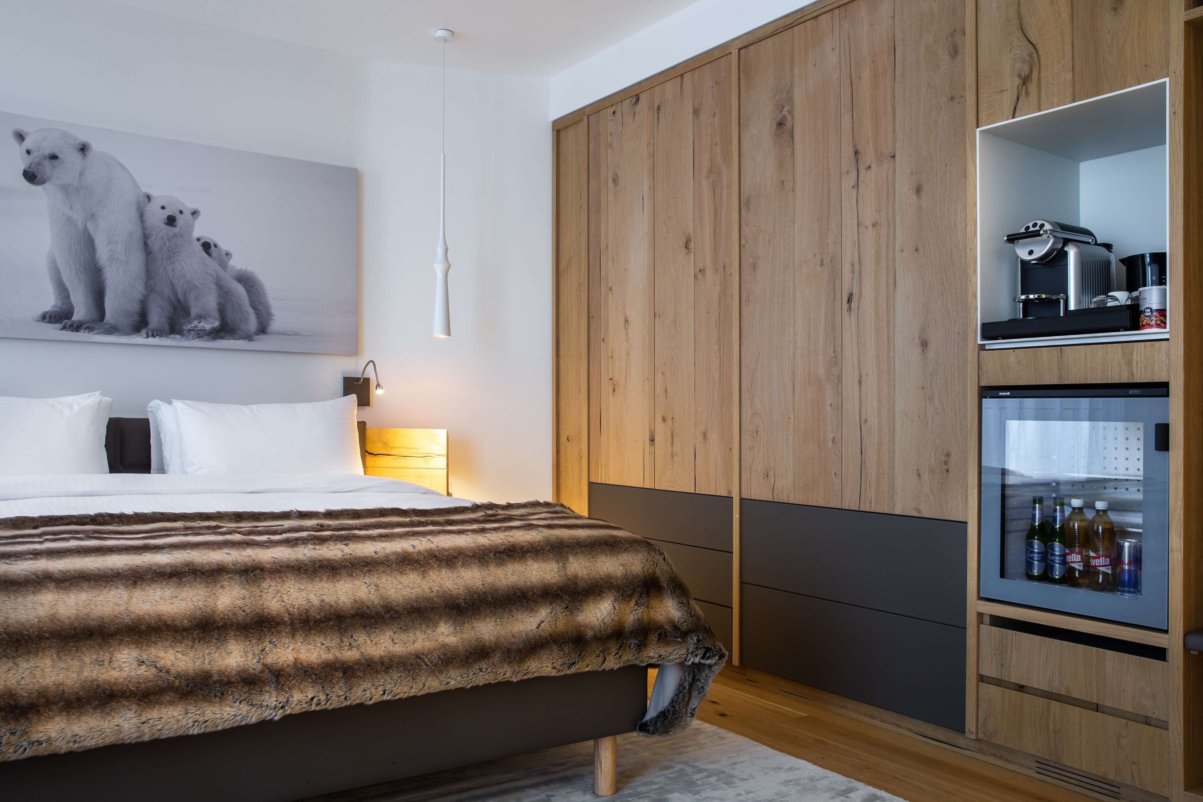 Ein modernes Schlafzimmer mit einem großen Bett, einem Holzschrank und einer Minibar.