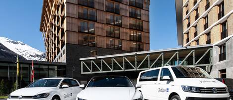 Tres automóviles Volkswagen blancos estacionados frente a un edificio con un diseño arquitectónico moderno, que presenta fachada de madera y ventanas amplias.