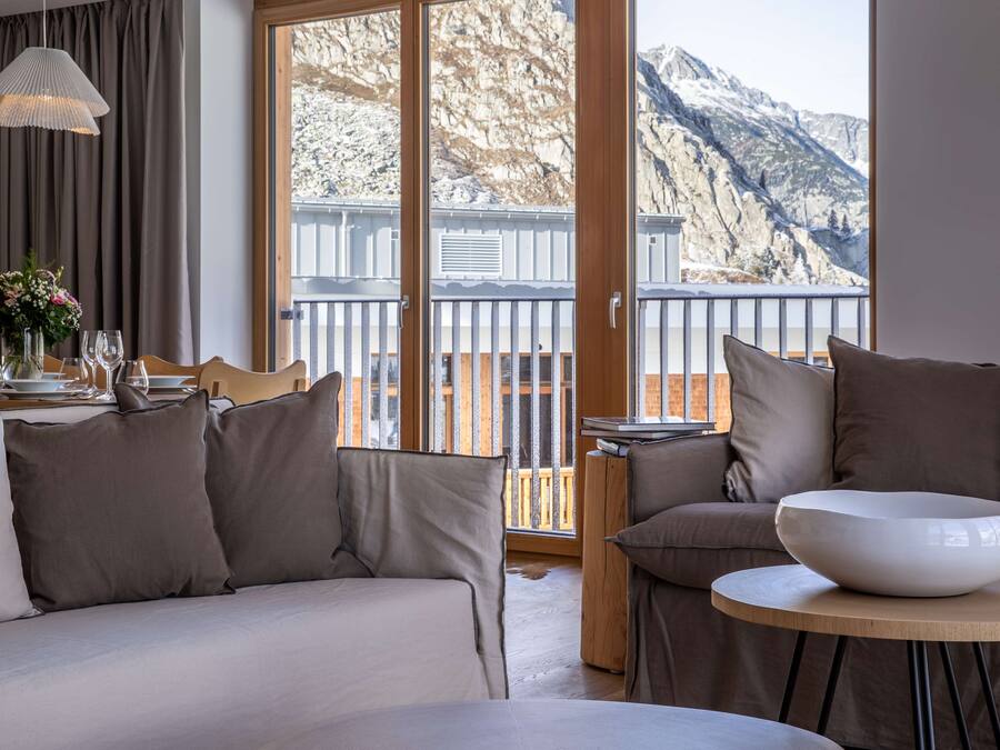 Ein modernes Hotelzimmer mit Balkon, Essbereich und Bergblick.