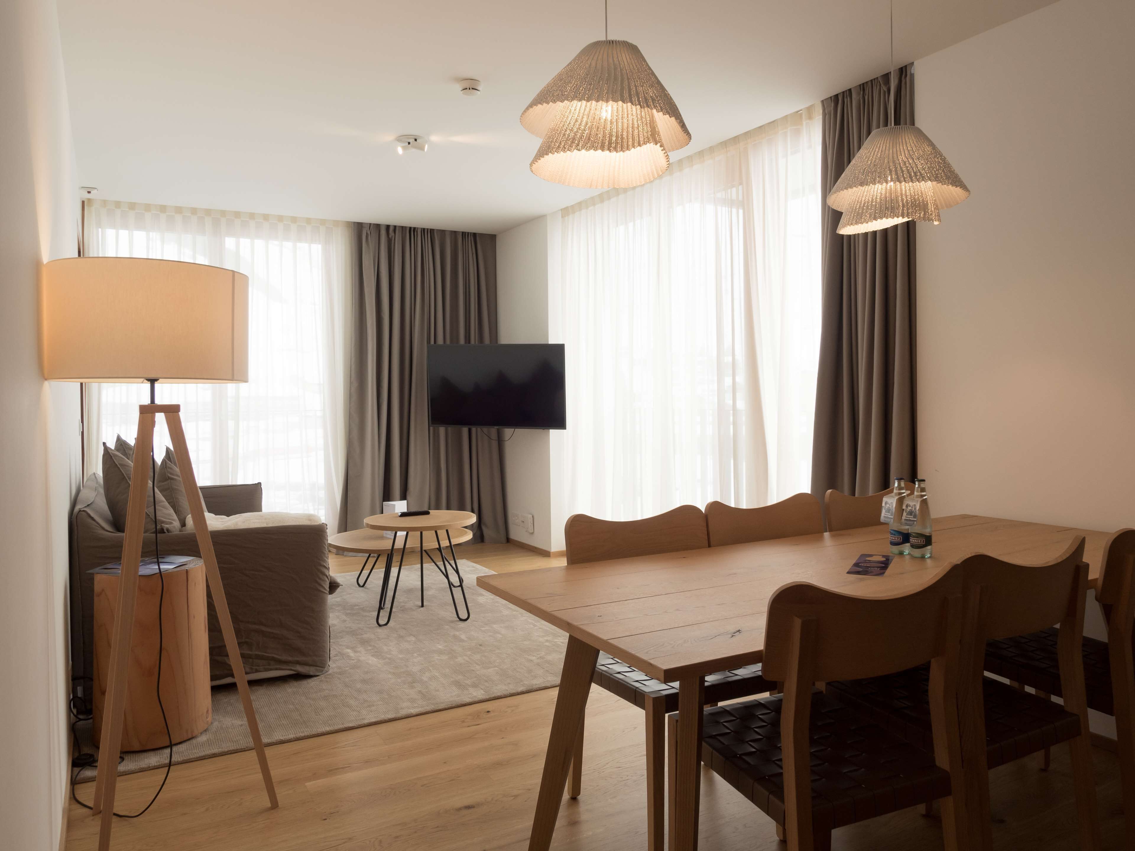 Une chambre d’hôtel moderne comprenant un coin repas, un canapé, une télévision et une lampe.