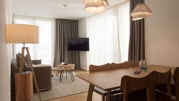 Une chambre d’hôtel moderne comprenant un coin repas, un canapé, une télévision et une lampe.