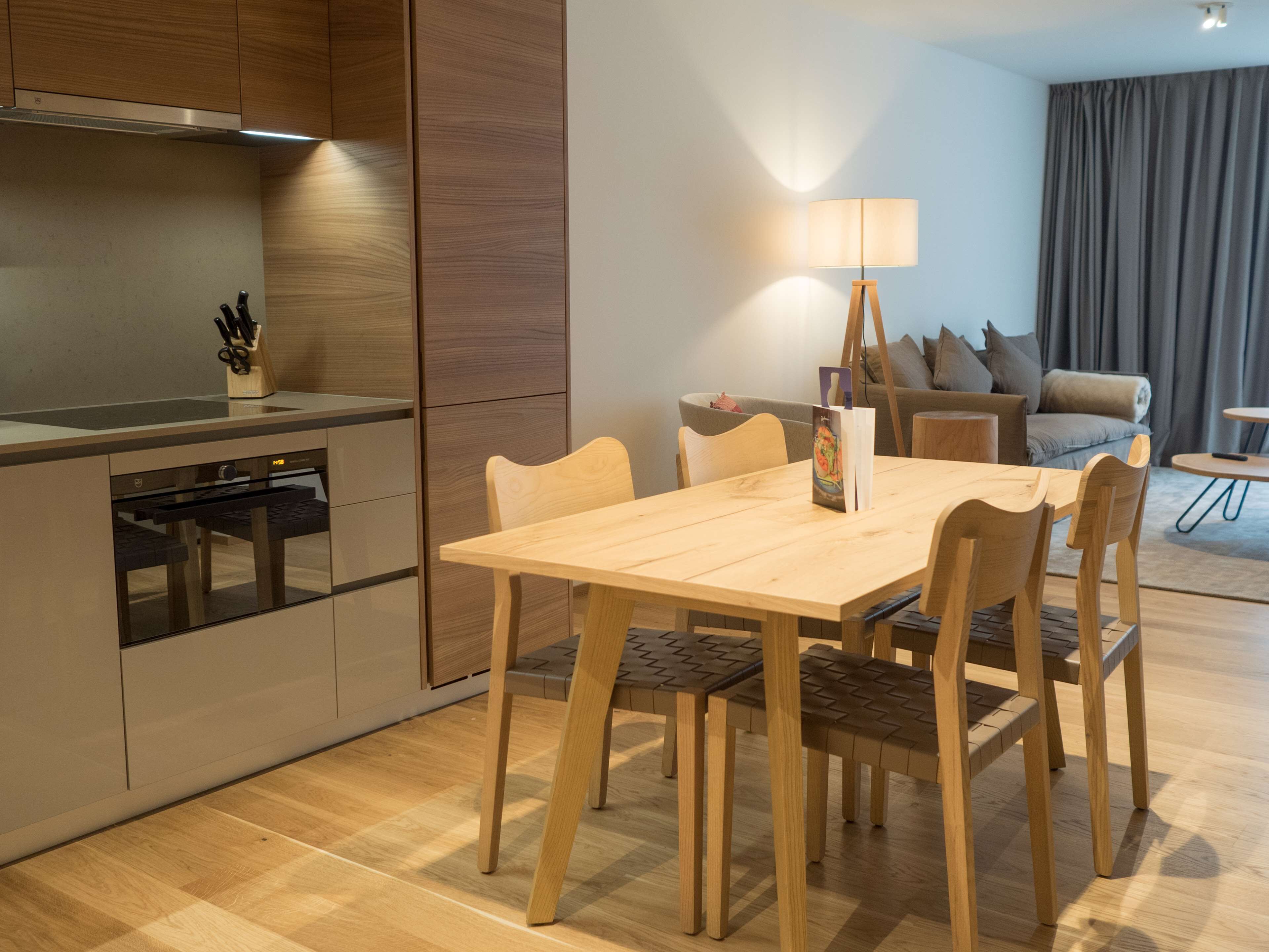 Eine moderne Küche mit Einbauofen und Essbereich mit Holztisch und Stühlen.