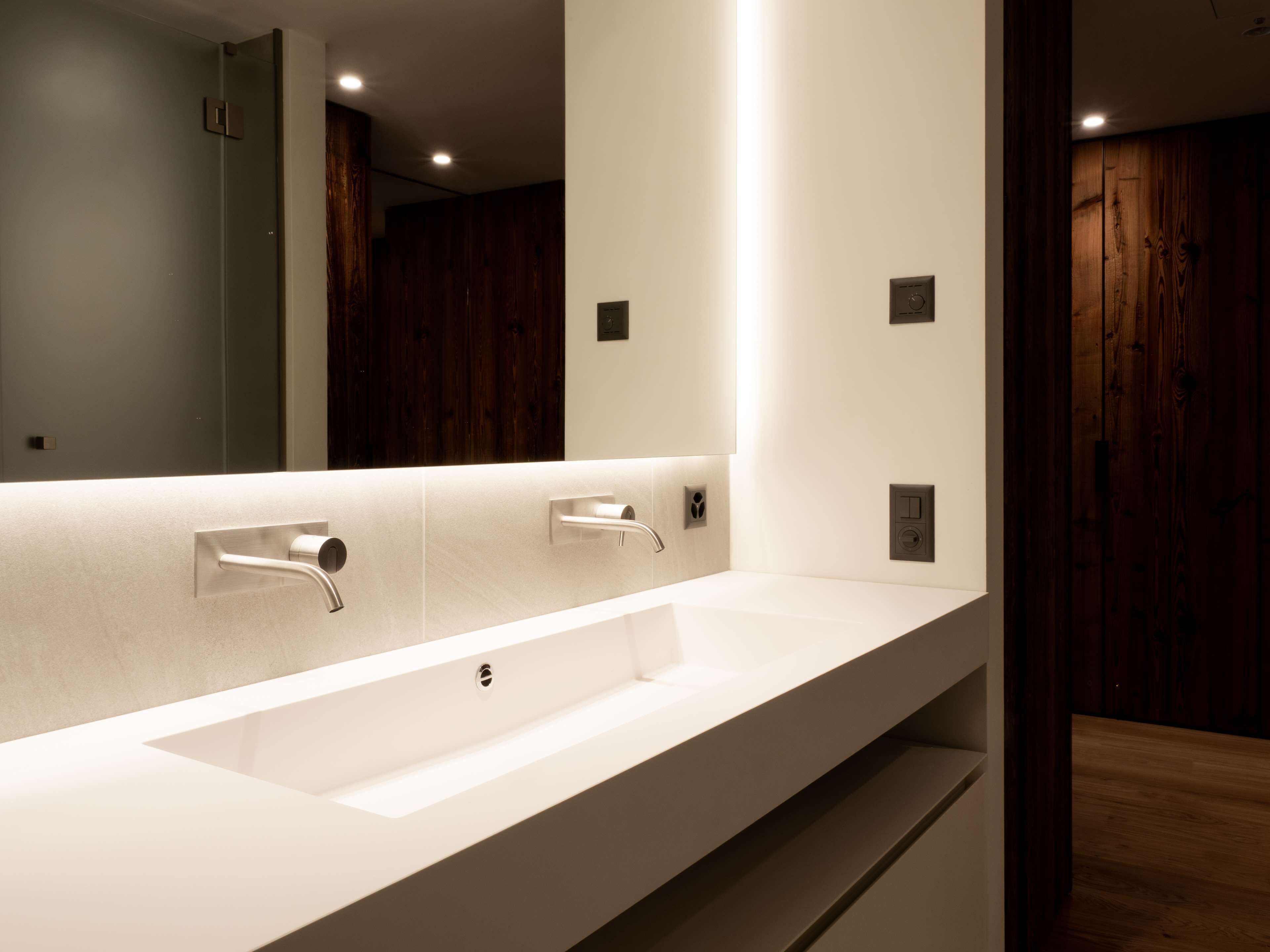 Een moderne badkamer met een grote spiegel, twee wastafels en houten lambrisering.