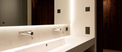 Un baño moderno con un espejo grande, dos lavamanos y paneles de madera.