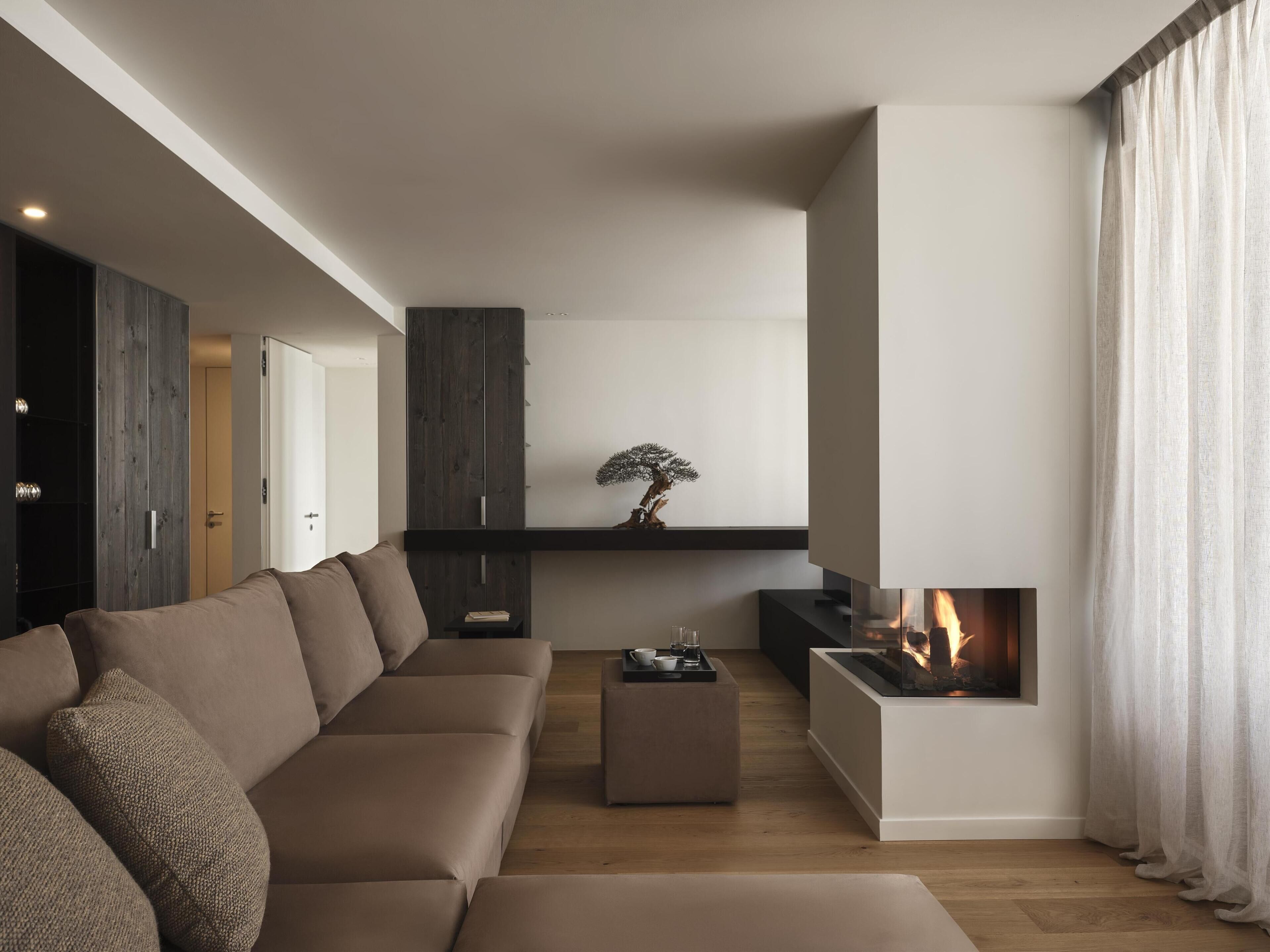 A modern living room with a sofa, a coffee table, a fireplace, and a bonsai tree.