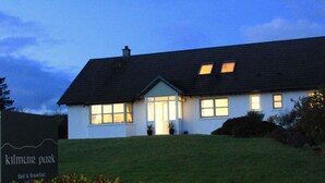 A two-story house with a sloped roof, large windows, and a well-maintained lawn. - Kilmuir Park (Dunvegan)