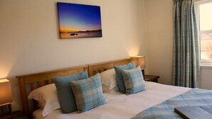 A neatly made bed with a blue and white checkered blanket, two pillows, and a laptop on the bed. - Kilmuir Park (Dunvegan)
