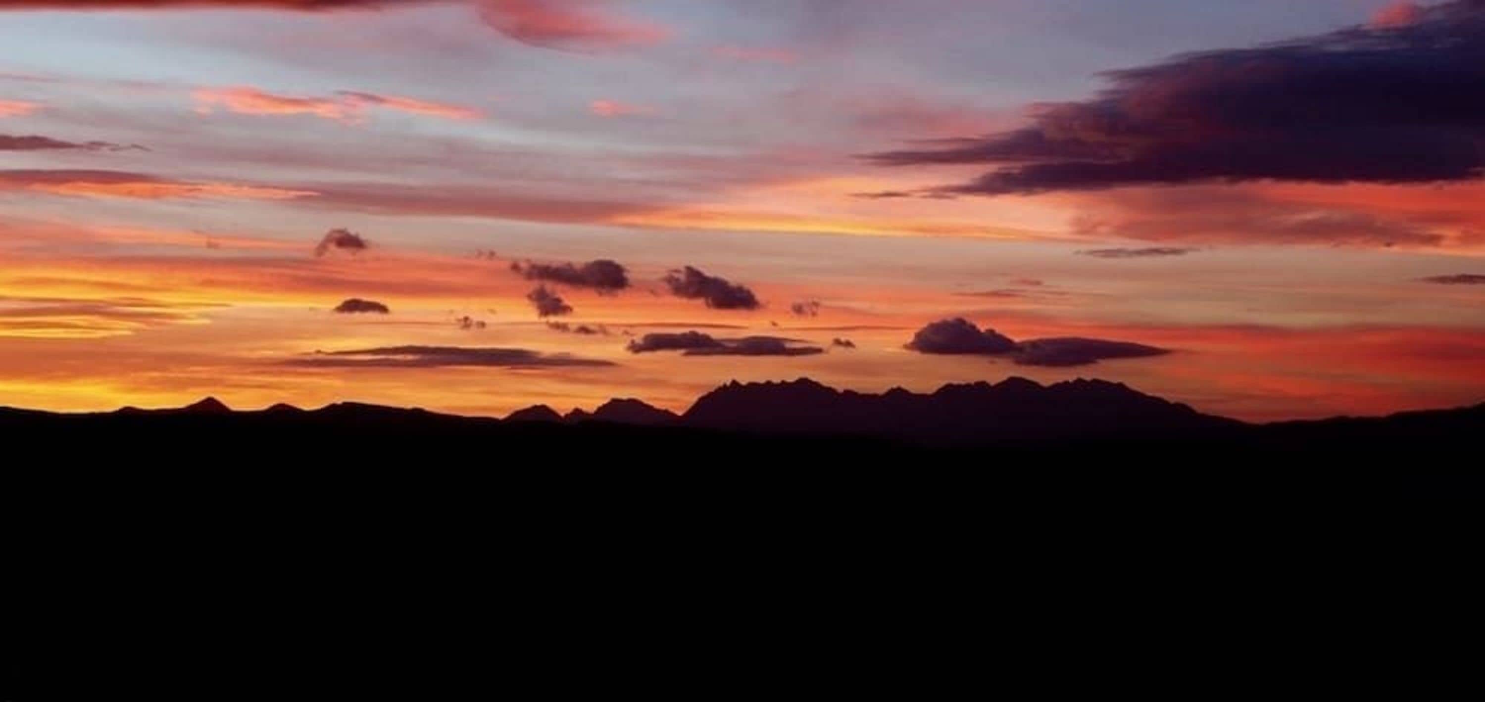 A mountain range silhouette against a sunset sky.