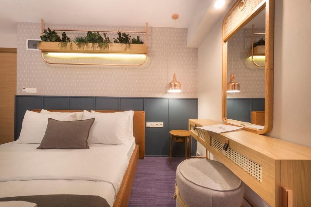 A hotel room with a bed, bedside table, chair, and a mirror.
