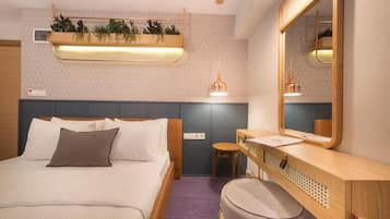 A hotel room with a bed, bedside table, chair, and a mirror.