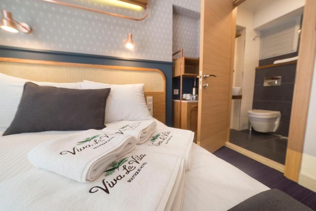 A hotel room with a bed, a bathroom, and a visible shower area.