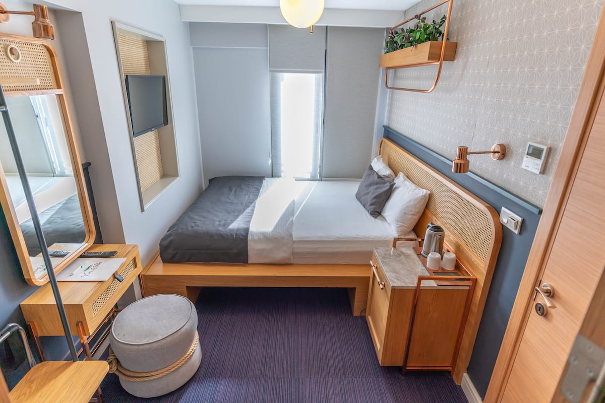 Habitació d'hotel senzilla amb llit, taula de nit i petita zona de seients.