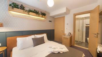 A hotel room with a bed, bedside table, a mirror, a shower, and a door.