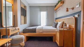 Ein gemütliches Schlafzimmer mit Bett, Schreibtisch, Stuhl, einem kleinen Hocker, einem Fernseher und einem Fenster.