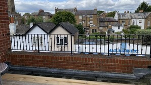 A residential area with a white house, a brick wall, and a metal fence. - 31b St Leonards Road (Windsor)