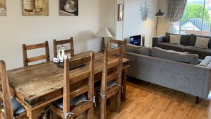 A cozy living room with a wooden dining table, grey sofa, and artwork on the walls. - 31b St Leonards Road (Windsor)