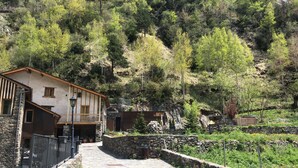A rustic mountain lodge with stone walls, a balcony, and a stone pathway leading to the entrance. - Cal Batlle Casa Rural (La Cortinada)