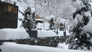 A snow-covered landscape with a stone wall and a sign that reads "BATTLE". - Cal Batlle Casa Rural (La Cortinada)