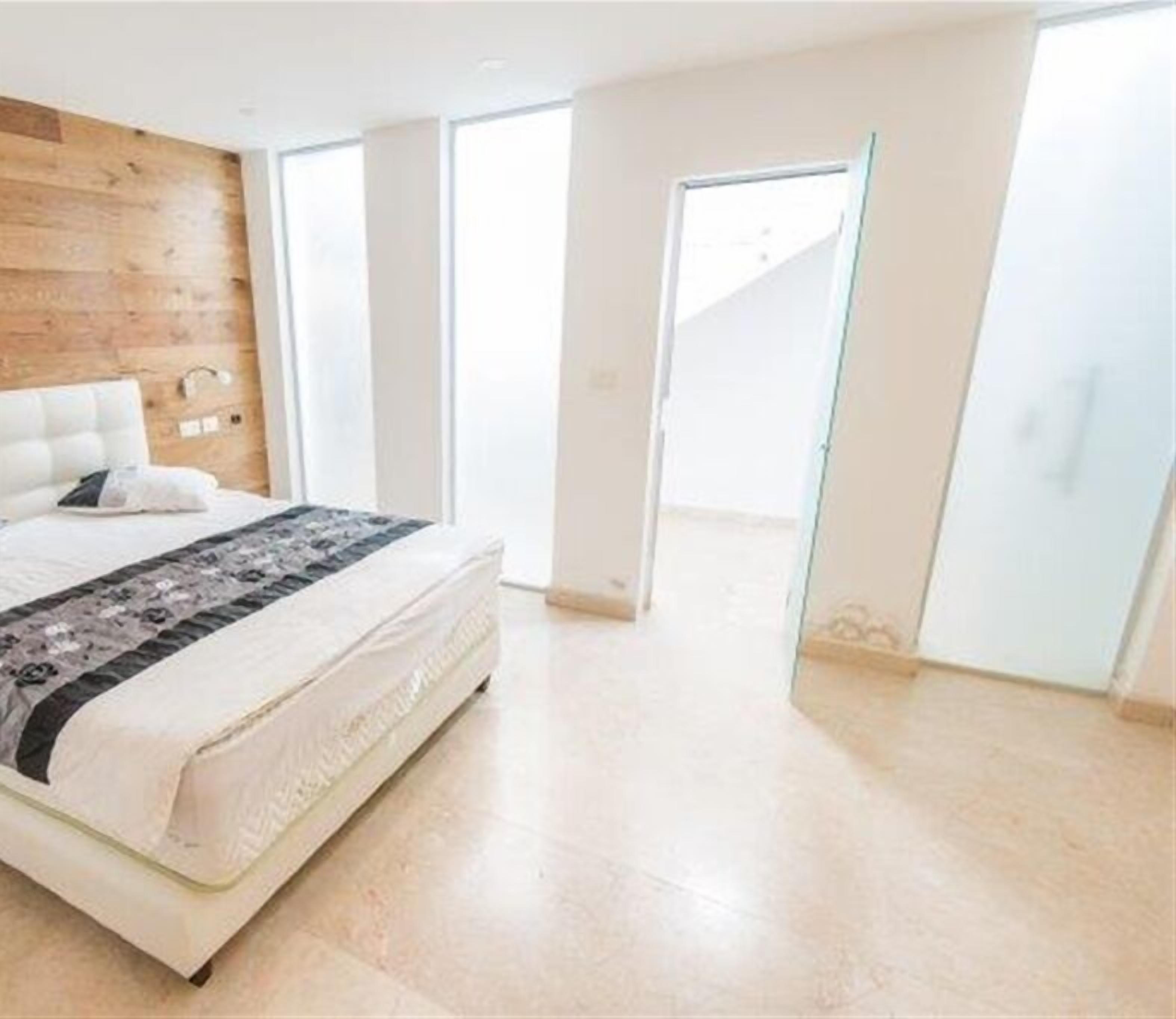 Un dormitorio con cama, una pared de acento de madera y un ventanal grande.