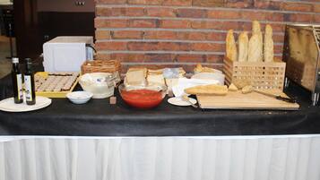 Una mesa de buffet con diversos alimentos, entre ellos pan, bollería y salsas.