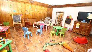 Un cuarto de juegos infantil con paredes de madera, una pizarra y diversos juguetes.