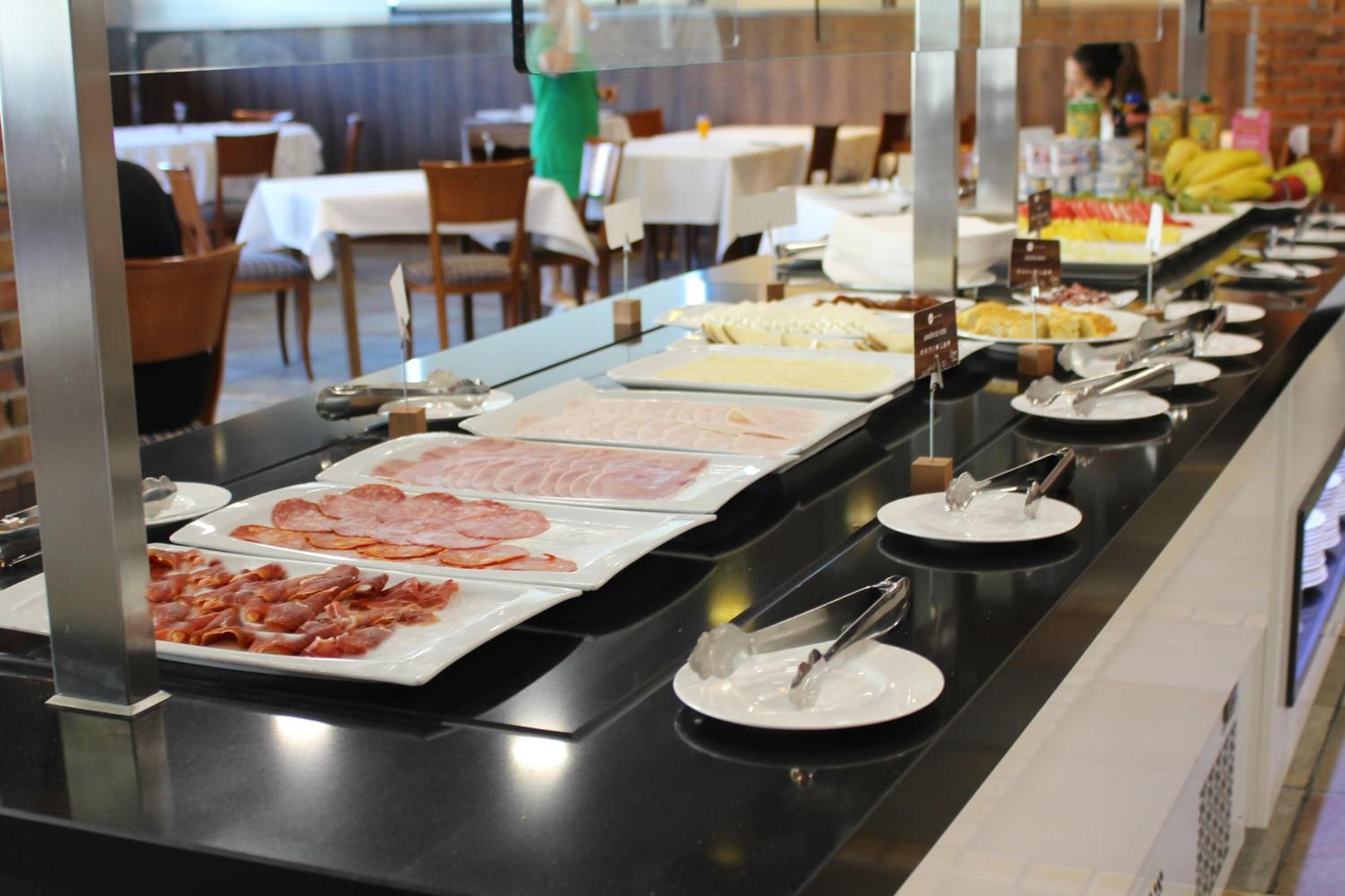 Ein Buffet mit verschiedenen Speisen, darunter Fleisch- und Käseauswahl, in einem Restaurant.