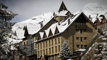 Situated in a mountainous region, this chalet-style building features a steeply pitched roof and multiple gabled roofs.