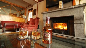 A fireplace with a TV above it, a bottle of Chivas Regal whiskey, and two glasses on a table. - YoY Villa de Sallent 4 (Sallent de Gallego)
