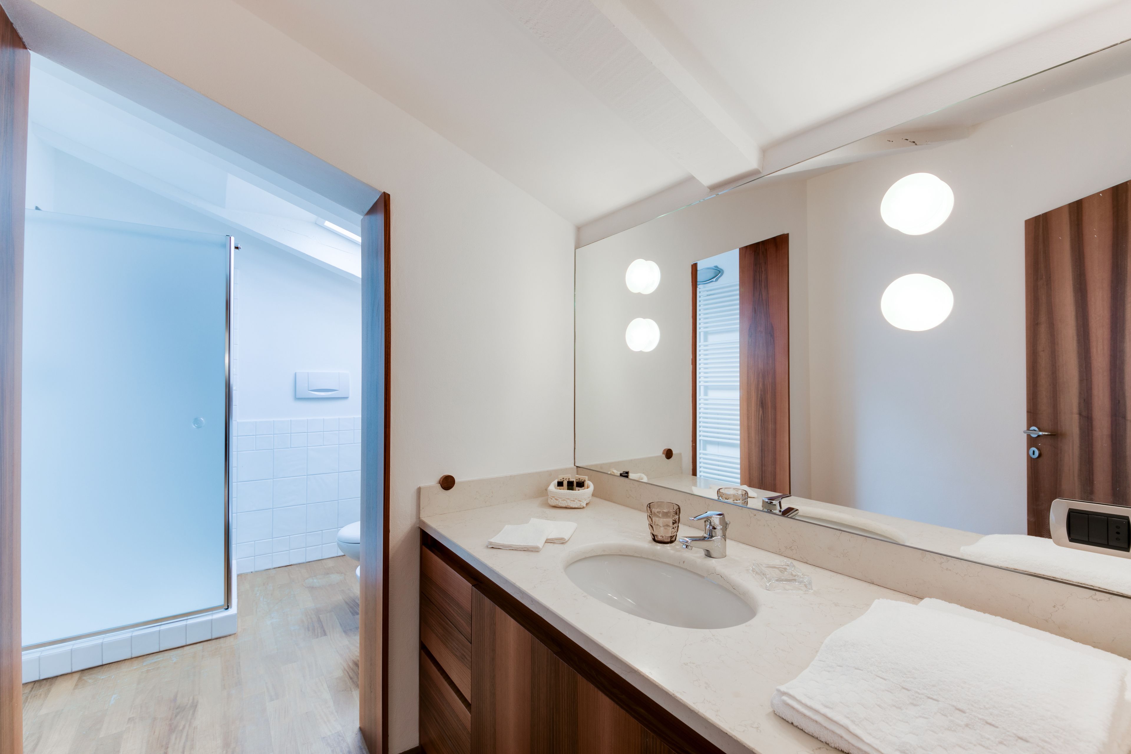 A modern bathroom with a large mirror, a sink, and a shower area.