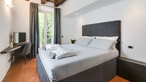A modern bedroom with a large bed, a desk, and a window with curtains.