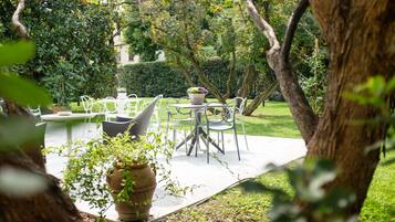 An outdoor patio with a table and chairs, surrounded by greenery and trees.