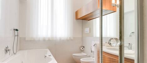 A modern bathroom with a bathtub, toilet, and shower area.