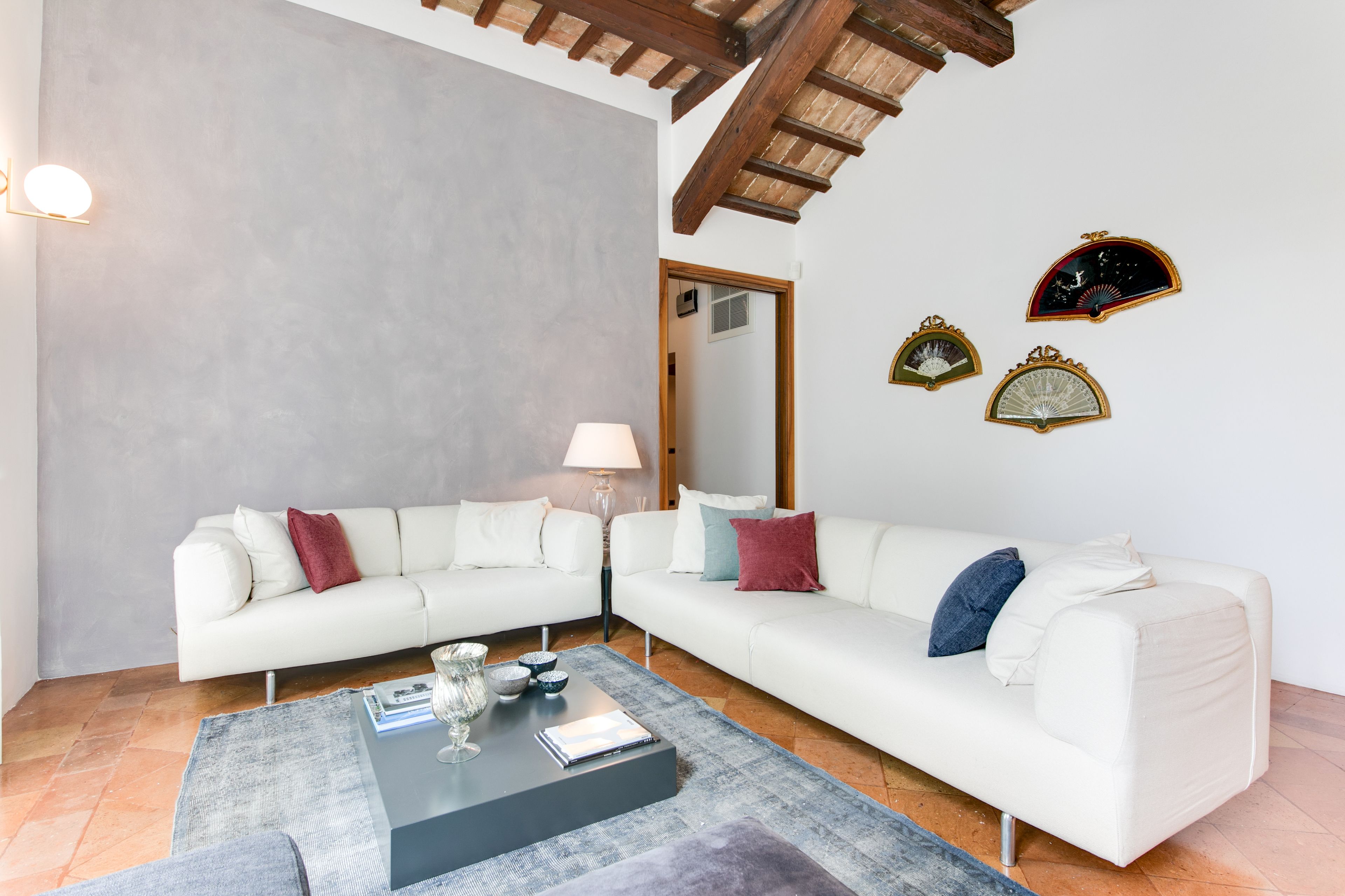Un salon moderne avec un canapé d’angle blanc, une table basse et des horloges décoratives murales.