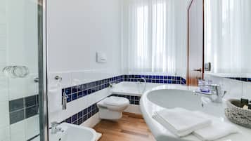 A modern bathroom with a glass shower enclosure, a freestanding bathtub, a toilet, and a sink with a towel rack.