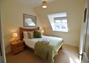 Relax in this cozy hotel room with a large bed, nightstand, and mirror.