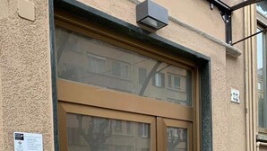 A large glass door with a handle, a small sign on the wall, and a utility box above the door. - Appartamento Gradisca (Lecco)